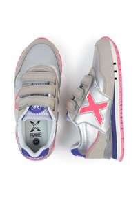 Zapatillas gris y plateadas con acentos rosas, tres correas de Velcro, lengüeta de malla y un detalle de talón púrpura. Suela de goma estable con tacos.