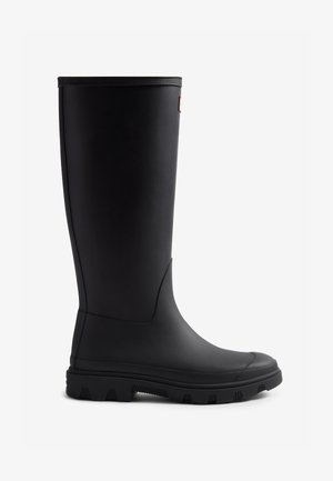 Botte de pluie en caoutchouc noir avec une surface lisse, un haut tige, une semelle à traction texturée et un subtil détail latéral, conçue pour une protection imperméable.