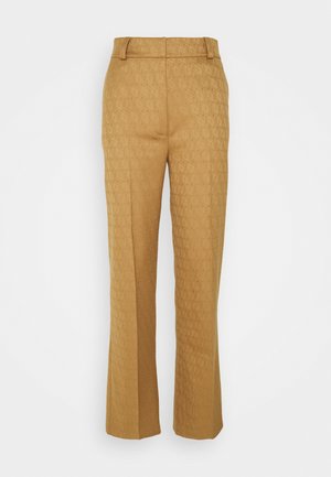 Pantalon tailleur taille haute couleur beige avec motif géométrique subtil, jambes droites et pli sur l'avant, présenté sur un fond blanc.
