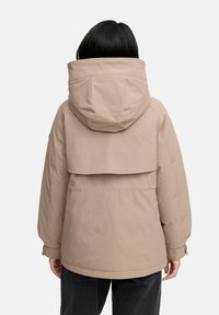 Beige jacket with a large hood, back flap, and elastic cuffs. Features a smooth texture and a loose, slightly oversized design.
