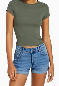 Olivgrön ribbad crop top med korta ärmar, matchad med ljusblå denimshorts med hög midja, rullade fållar och framfickor.
