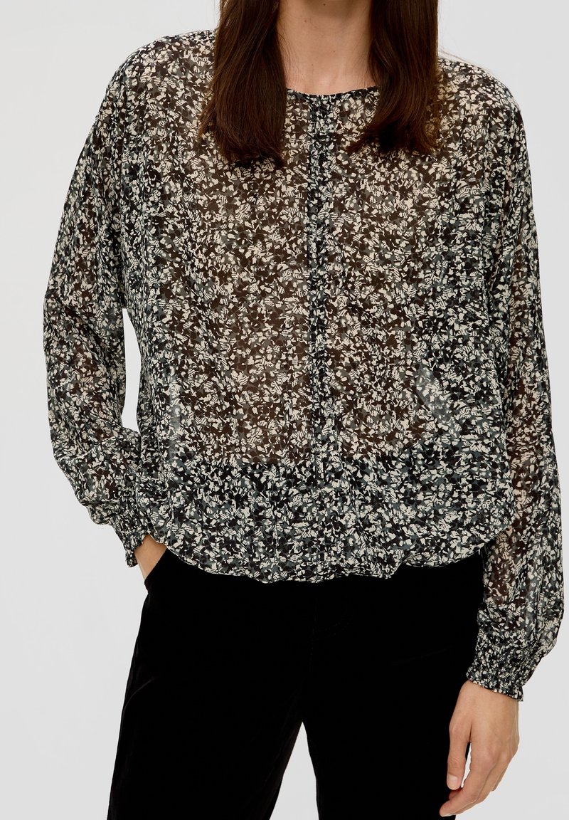 Schwarze blumenverzierte transparente Bluse mit rundem Ausschnitt, langen Ärmeln, gerafftem Saum und zarten weißen und grauen Blumenmustern.