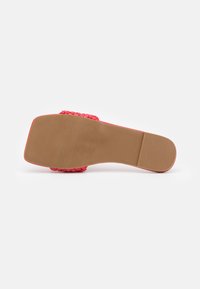 Sandale slide synthétique rouge avec tige tressée, semelle plate dotée de rainures pour une meilleure adhérence, et une semelle en caoutchouc lisse marron.