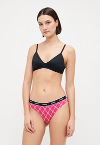 Svart trekantet bralette med tynne stropper, parret med rosa mønstrede truser med svart elastisk midjebånd med "HUGO"-merke.