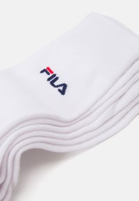 Fehér pamut crew zoknik halmozva, vörös és tengerészkék akcentusokkal ellátott logóval. Texturált felső rész a kényelem és a légáteresztő képesség érdekében.