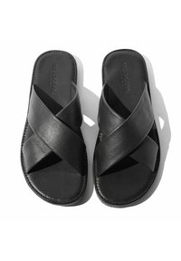 Crne kožne sandale s dizajnom prekriženih naramenica, ravnim potplatom i glatkom teksturom. Logo proizvođača je utisnut na ulošku.