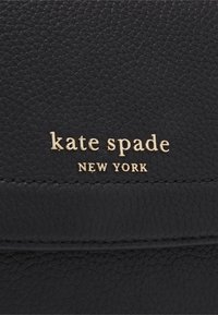 Musta nahkalompakko, jossa on teksturoitu pinta. Siinä on kultainen kohopainettu "kate spade NEW YORK" -logo, koristeltu siistillä ompeleella.