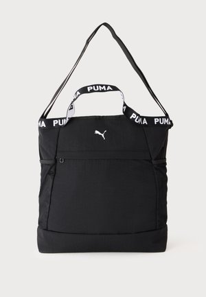 Sort Puma tote taske med to håndtag, en justerbar skulderstrop, netlommer på siderne og et lille hvidt Puma-logo foran.