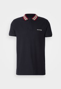 Polo bleu marine en coton, avec un col rayé rouge, blanc et noir. Comprend un petit logo blanc "HILFIGER" sur la poitrine.