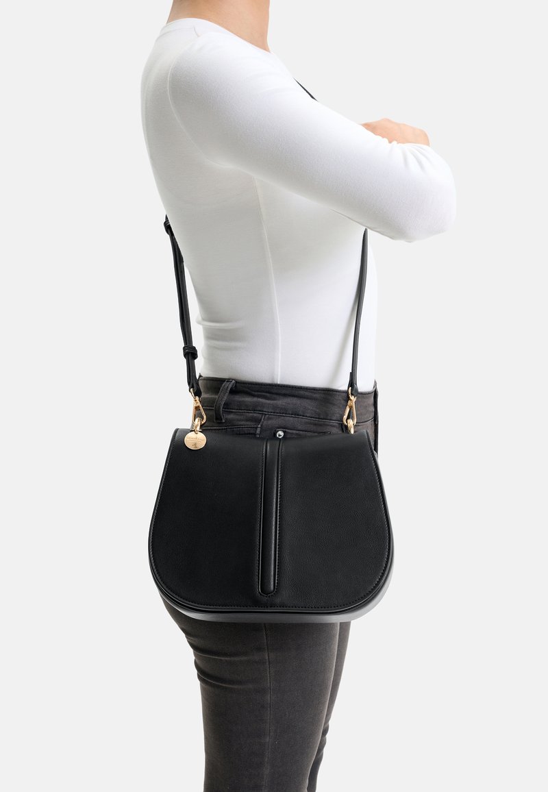 Black leather shoulder bag with a rounded shape, top flap, and gold hardware accents. Features a smooth texture and adjustable strap.