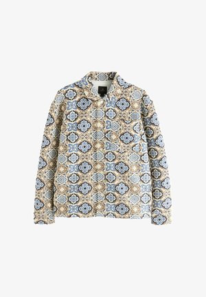Veste matelassée avec une base beige, présentant un motif bleu et marron. Elle a un col et des fermetures à bouton visibles.