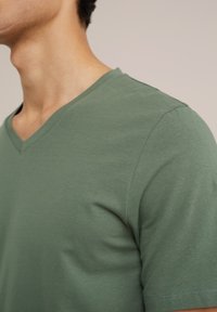 Kortærmet V-hals t-shirt i olivengrønt bomuld med en glat tekstur og slim fit, med afsluttede sømme og en ren halsudskæring.