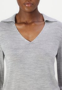 Grauer Strickpullover mit V-Ausschnitt und Kragen. Der Stoff hat eine glatte Textur mit einem dezenten melierten Muster. Lange Ärmel.