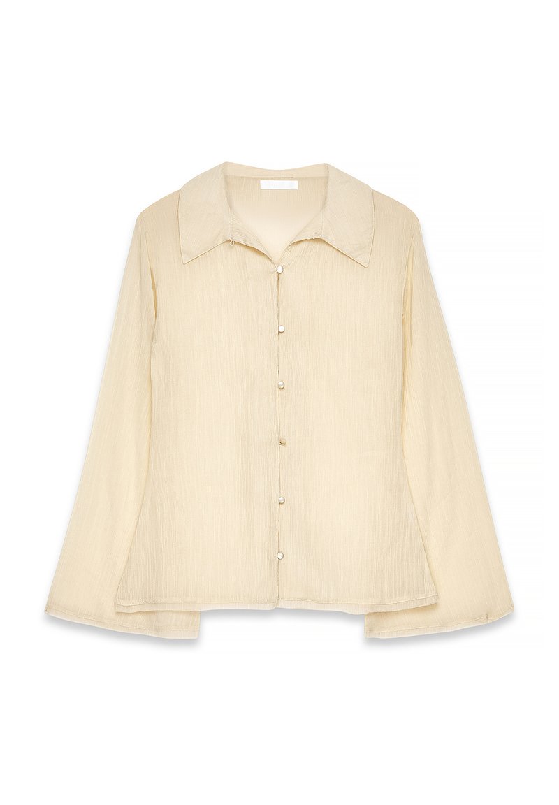 Camicia beige a maniche lunghe con colletto appuntito, chiusura con bottoni e tessuto testurizzato. L'orlo è leggermente curvo con una vestibilità rilassata.