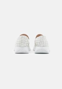 White sneaker with a textured embossed pattern, rounded toe, and light rubber sole featuring cloud engravings on the heel.