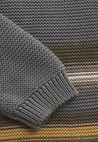 Grå stickad tröja med ribbad mudd. Har horisontella ränder i olika jordtoner: brun, krämfärgad och senapsgul. Texturerad tyg.