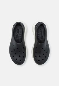 Svarte slip-on sko med perforert overdel og en hvit, teksturert såle. Innvendig har de en formet fotseng med "CROCS" merke.