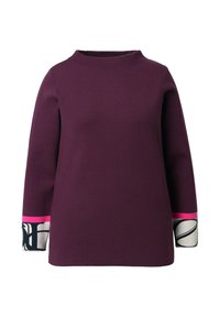 Maglietta viola a maniche lunghe con un collo alto. Presenta dei polsini colorati in rosa e dettagli a motivi in bianco e nero.