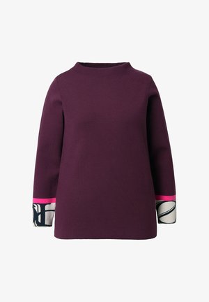 Maglietta viola a maniche lunghe con un collo alto. Presenta dei polsini colorati in rosa e dettagli a motivi in bianco e nero.