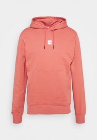 Sudadera con capucha en color coral, hecha de tejido suave, con un bolsillo frontal y un pequeño parche de logo. Puños y dobladillo acanalados.