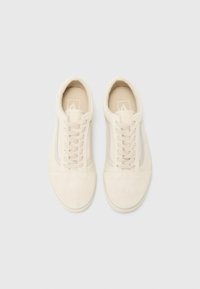 Beige suede sneakers with a smooth finish, rounded toe, and laces. Side features a subtle stripe pattern. Minimalist design, flat outsole.