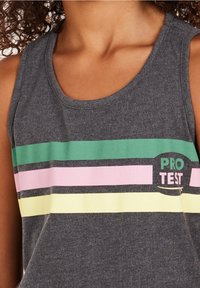 Canottiera grigia scura senza maniche con strisce orizzontali verdi, rosa e gialle e testo "PRO TEST" sul petto sinistro.