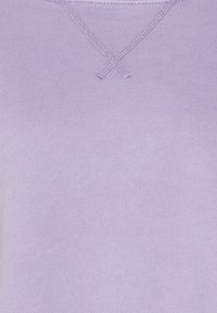 Lila tröja med ett slätt, texturerat tyg och en V-formad sömdetalj vid halsen. Enkelt designad utan mönster eller dekorationer.