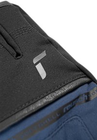 Svart softshellmaterial med en grå logo. Har platta sömmar och en blå insida. Slät textur med en lätt glans.