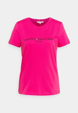 Różowy T-shirt z krótkim rękawem wykonany z bawełny. Posiada czarne logo "TOMMY HILFIGER" oraz małą emblemat w centrum, z okrągłym dekoltem.
