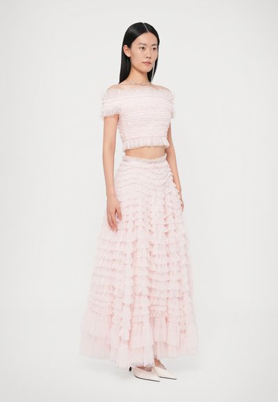 Σετ δύο τεμαχίων που περιλαμβάν�ει ένα τοπ κορυφαίο με βολάν και μια μακριά φούστα που ταιριάζει, και τα δύο από ανοιχτό ροζ τούλι με στρωμένα βολάν. Διαθέτει σχέδιο με ακάλυπτους ώμους.