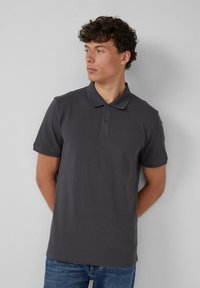 Korte mouwen, donkergrijze polo met een kraag, twee-knopen placket en subtiel textuurstof, gecombineerd met blauwe jeans.