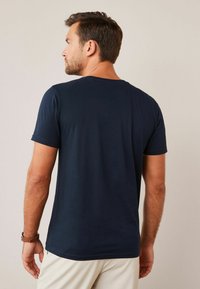 Tricou scurt din bumbac moale, de culoare bleumarin, cu gât clasic rotund și un design ajustat. Textură simplă și netedă.