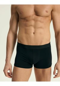 Czarne majtki boxerki wykonane z gładkiego materiału. Posiadają dopasowany krój, elastyczny pas i minimalne detale szwów.