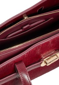 Burgundy handbag featuring smooth leather and a textured fur-like panel, with gold-tone hardware and multiple interior pockets.
