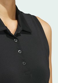 Polo noir sans manches avec un col à revers, une patte de boutonnage à trois boutons, et une finition en tissu lisse et texturé.