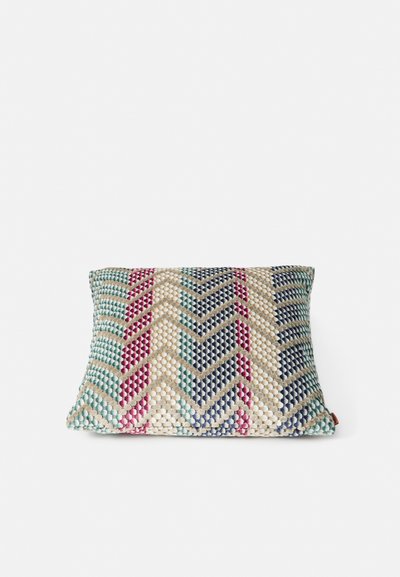 Teksturet puter med et geometrisk zigzag-mønster i teal, rosa og marineblå på en naturlig bakgrunn; kvadratisk form med et sideetikett.