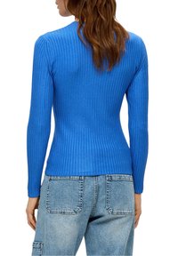 Top a maniche lunghe in blu brillante, con una silhouette aderente e scollo rotondo, abbinato a pantaloni in denim azzurro.