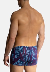 Pánské plavky ve výrazném modro-fialovém zebrovaném vzoru, s elastickým pasem a těsným střihem kolem stehen.