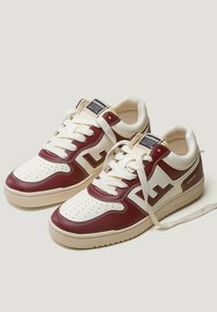 Białe i burgundowe skórzane sneakersy z perforowanym przodem, płaskimi sznurowadłami oraz brandingiem na języku i boku; amortyzowana podeszwa.