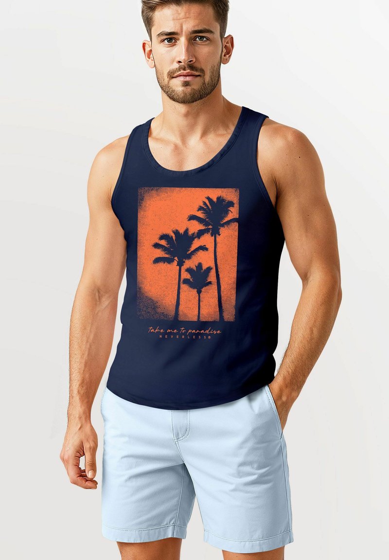 Ein junger Mann trägt ein dunkelblaues Tanktop mit einem orangefarbenen Palmenmotiv und dem Schriftzug "Nimm mich mit ins Paradies", kombiniert mit hellblauen Shorts.