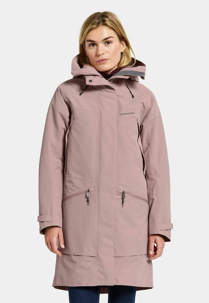 Parka impermeable de un suave color rosa claro con capucha, que cuenta con bolsillos con cremallera, puños ajustables y un corte relajado. El material es suave, con acentos mínimos.