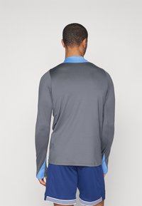 Langärmliges Sportshirt in Grau mit einem hellblauen Kragen und Akzenten an den Ärmeln, aus glattem, leichtem Material gefertigt.
