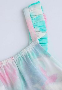 Lekki, pastelowy materiał tie-dye w odcieniach turkusu, różu i bieli. Posiada falbaniasty pasek i zgomadzone elastyczne wykończenie dekoltu.