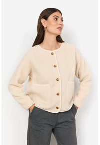 Beige fleecejacka med rundad halsringning, knäppning fram, två framfickor och kontrasterande kant. Mjuk, texturerad tyg med en avslappnad passform.