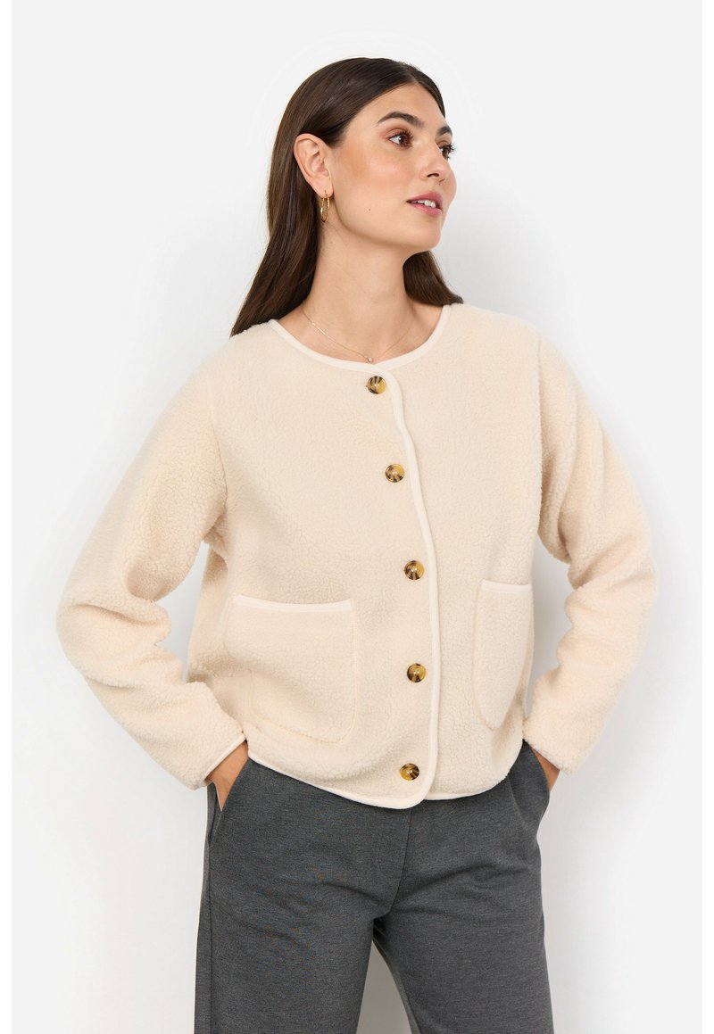 Beige fleecejacka med rundad halsringning, knäppning fram, två framfickor och kontrasterande kant. Mjuk, texturerad tyg med en avslappnad passform.