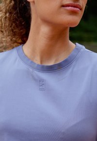 Maglietta atletica a maniche corte lavanda con texture a costine, scollatura a girocollo e un logo goffrato discreto sul petto.