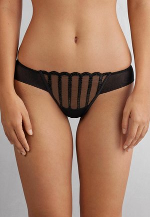Zwarte mesh thong met geschulpte kantdetails aan de voorkant, een doorschijnend paneelontwerp en soepele stof aan de zijkanten.