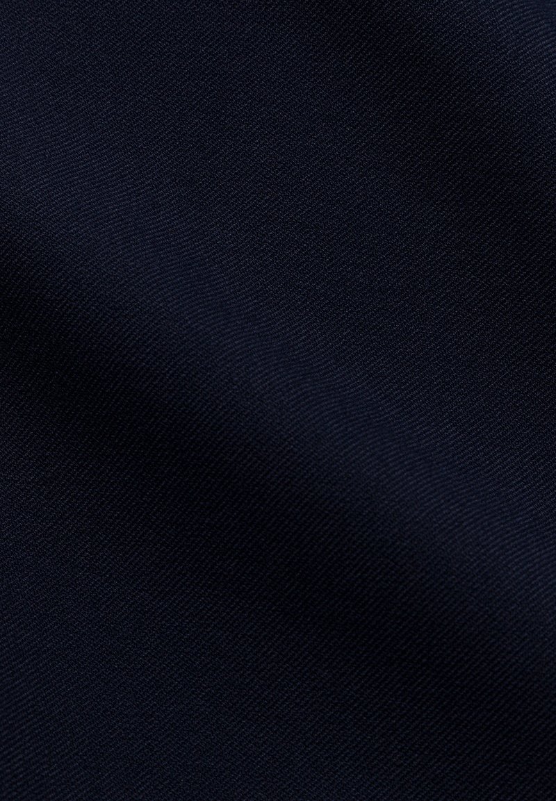 Nahaufnahme eines glatten, dunkelblauen Stoffes mit subtiler diagonal verlaufender Webstruktur und sanften Falten.