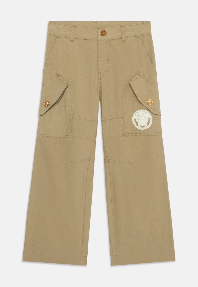 Beige cargo bukser laget av bomull med vide ben, som har to sidelommer, gullknapper og et Medusa-logo-patch på høyre ben.