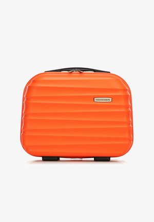 Oranžový tvrdý kufr s rýhovaným povrchem, černými madly a zlatým logem. Kompaktní obdélníkový tvar se čtyřmi kolečky na spodní části.